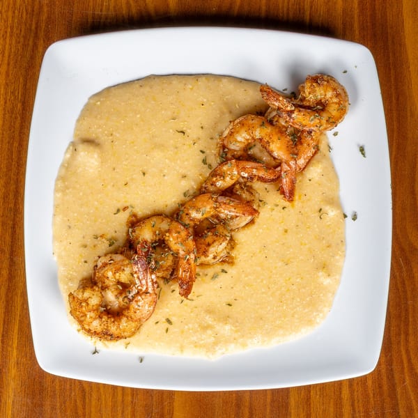 Melvin's at Riverside's shrimp and grits, a southern dish, on a white plate.